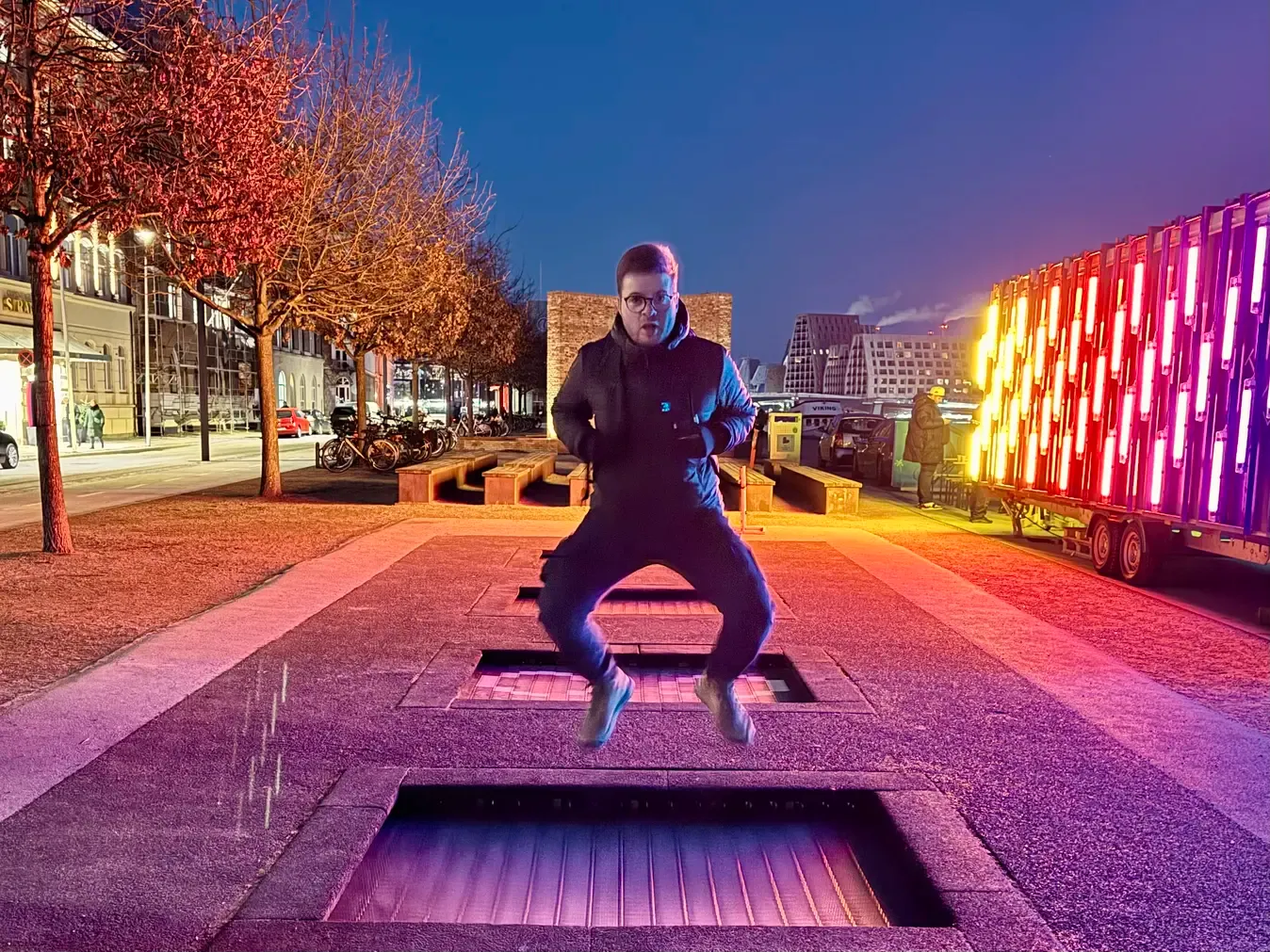 A photo of me (Thib) jumping on a trampoline in the street at night, with flashy neon lights on the side.